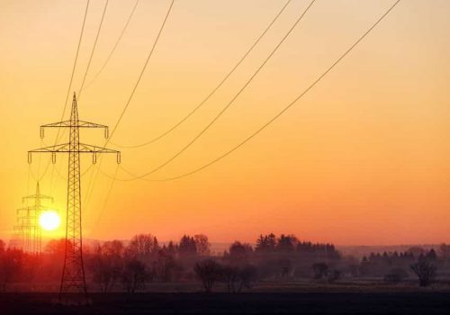 eine Hochspannungsleitung mit auf- oder untergehender Sonne